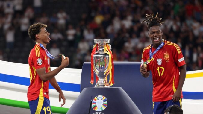 Spain's forward #19 Lamine Yamal (L) and Spain's midfielder #17 Nico Williams celebrate on the podium after winning the UEFA Euro 2024 final football match between Spain and England at the Olympiastadion in Berlin on July 14, 2024. (Photo by Adrian DENNIS / AFP)